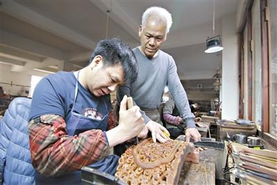 中国侨网胡敏强（右）在指导年轻人雕刻红木。 