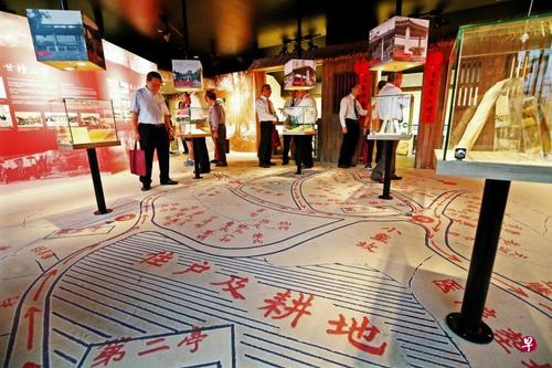 中国侨网策展人将广惠肇碧山亭文物馆的地板贴上昔日甘榜山亭的地图,构思巧妙,展览也透过媒体、实物和照片方式呈现昔日甘榜山亭的生活。(新加坡《联合早报》/梁麒麟 摄)