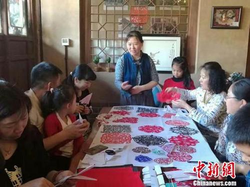 中国侨网白海燕为前来学习剪纸的家长和小朋友讲述剪纸技艺。　钟欣　摄