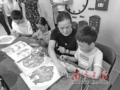 中国侨网国家级非遗项目(潮阳剪纸)省级传承人郑少燕现场教授孩子剪纸。 杨可 摄