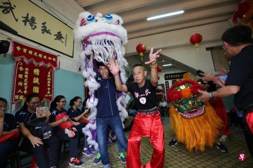 中国侨网博文中学学生林柏恩（左）参观新加坡精武体育会时，在师傅的指导下舞狮。（新加坡《联合早报》/梁麒麟 摄）