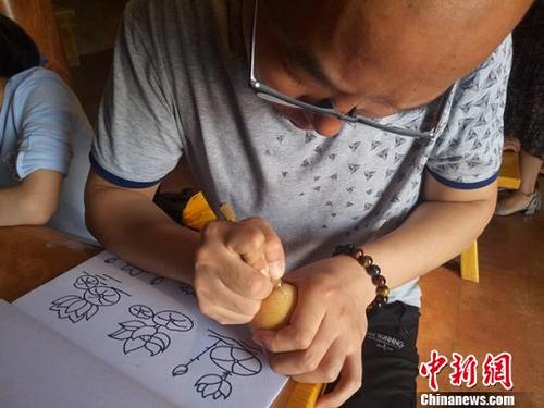 中国侨网图为游客在“鸡蛋”葫芦上雕刻荷花。　闫姣　摄