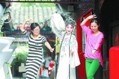 中国侨网在正乙祠内，两名参观者正在跟随戏曲演员学习戏曲表演动作。本报记者 方非摄