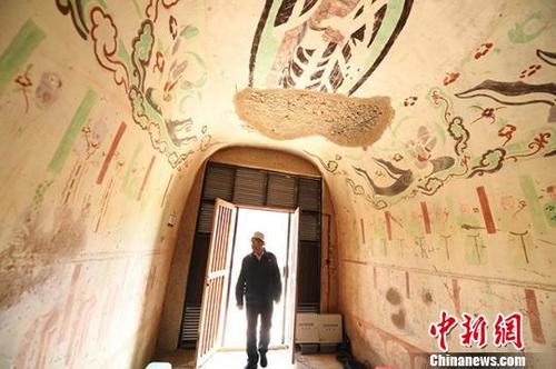 中国侨网8月上旬,甘肃敦煌室外的气温高达30多度,敦煌研究院“高龄”修复师李云鹤推开窟门,走进洞窟。 杨艳敏 摄