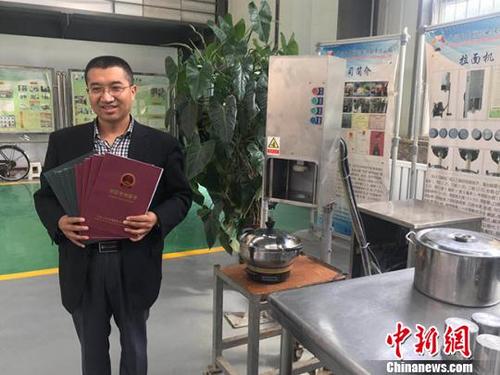 中国侨网经过6年的概念开发和产品规划、详细设计、小规模生产等阶段,李万祥设计的第四代拉面机于2016年正式投产销售。图为李万祥和机器的合影。 艾庆龙 摄
