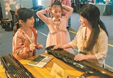 中国侨网会展现场,小朋友对古琴演奏充满了好奇。