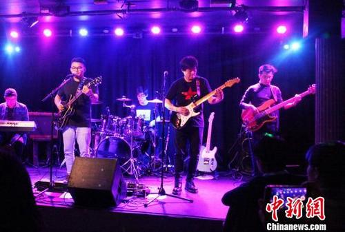 中国侨网12月5日晚，英国华人企业家和钟表鉴赏收藏家庆龙（右2）担纲主演的英国首支华人摇滚乐队“月球背面”在演出中。　张平　摄