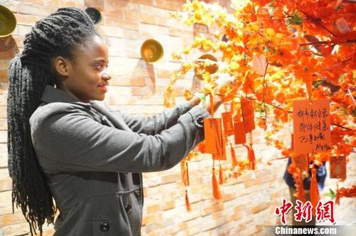 中国侨网图为外国友人在祈福树上挂上祈福牌。　韩章云　摄