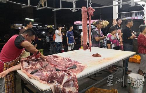 中国侨网员工在一旁的桌子上处理生猪,但无阻食客在一旁耐心等候,也成为一道风景。(马来西亚《星洲日报》)