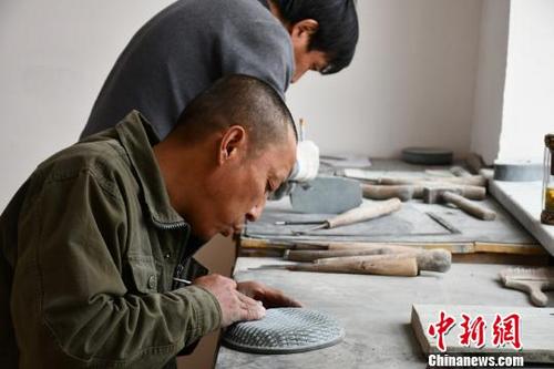 中国侨网图为村民在扶贫车间里雕刻洮砚。　魏金龙　摄