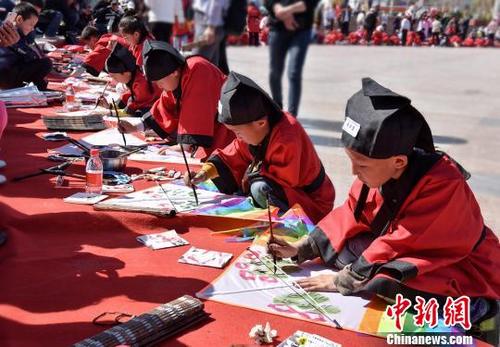 中国侨网4月20日,甘肃省嘉峪关市举办华艺汉芳·首届嘉峪关临风杯书画风筝节。图为青少年身着汉服认真绘制风筝。 师永红 摄