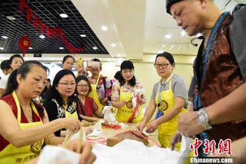中国侨网 马践在讲解捆扎法的操作要点,旁边的市民拿出手机进行记录。 王以照 摄