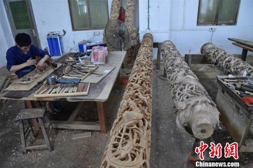 中国侨网 经过木雕艺人的巧手雕刻，祥云、花朵、麒麟、龙等图案逐渐显现。　陈龙山　摄