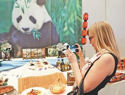 中国侨网图为活动现场，参观者在展台前拍摄具有四川文化特色的展品。本报记者 朱东君摄