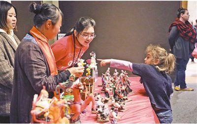 中国侨网 1月26日,美国国立亚洲艺术博物馆举办中国农历新年家庭日活动。图为一名美国小朋友向中方人员了解中国面塑作品。 本报记者 郑 琪摄