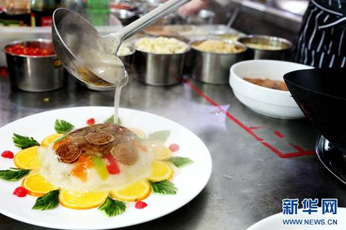 中国侨网范增福正在给八宝饭浇汁。八宝饭作为“老八盘”中的热菜之一,因其香甜的味道与软糯的口感深受食客们的喜爱。(新华网/卡娅梅朵 摄)