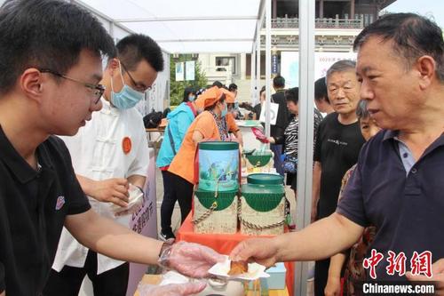 中国侨网在非遗购物节上，工作人员向市民推销济南超意兴的把子肉。（资料图）　赵晓　摄