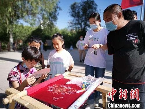 中国侨网8岁小绣娘正在刺绣作品，吸引游客驻足围观。　叶翠　摄