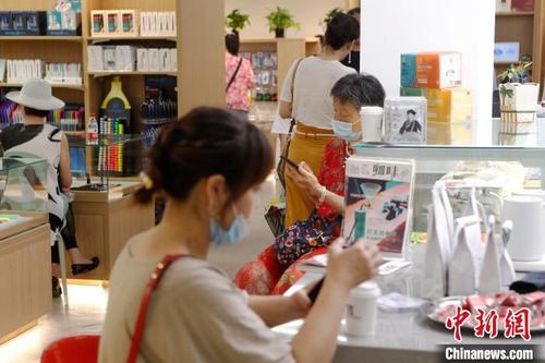 中国侨网市民在百新书局一边喝咖啡、一边查阅手机信息。　殷立勤　摄