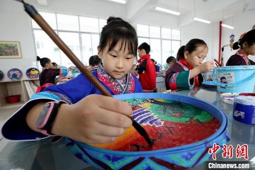 中国侨网11月6日，在广西三江侗族自治县民族实验学校，学生们在簸箕上绘制侗画。　吴练勋　摄