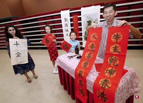 中国侨网来自印度的莎睿涵(左起)、宋家瑛和妹妹宋家娴,以及2021年N立方全国书法大赛最年长参赛者洪广和,一起展示他们的作品。(新加坡《联合早报》/梁麒麟 摄)