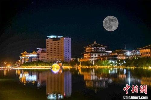 中国侨网5月26日深夜，一轮超级圆月悬挂在敦煌党河风情线上。（图片为双重曝光）。　王斌银　摄