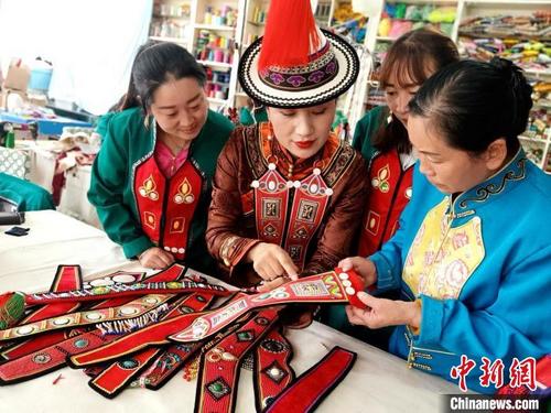 中国侨网图为裕固族服饰非遗传承人(左二)教授裕固族农牧民服饰刺绣。史静静 摄
