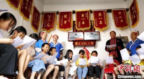 中国侨网吴通贤(后右二)给学生们教唱苗族“刻道歌”。奉力摄