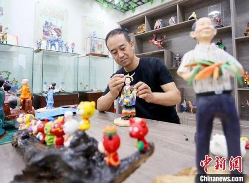 中国侨网8月31日,甘肃省非遗项目成州面塑传承人安秋平在用混有高粱、糯米的面泥制作面塑作品。 高展 摄