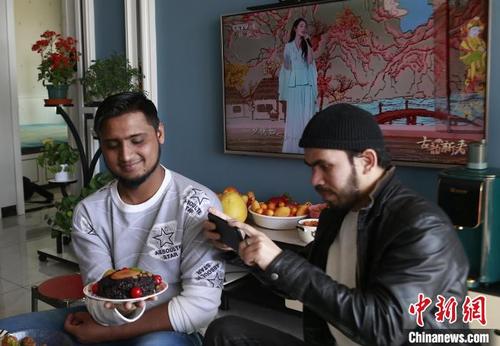 中国侨网图为来自孟加拉国的留学生白实德（右）拍摄特色美食“八宝饭”留念。　马铭言　摄