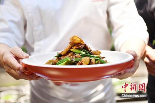 中国侨网四川成都,在一家打着“三代人都爱吃的回锅肉”招牌的川菜店内,厨师王加强展示自己刚做的川菜回锅肉。中新社记者 张浪 摄