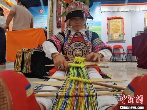 中国侨网6月8日，甘肃省张掖市，甘肃甘南藏族自治州舟曲县藏族姑娘，向民众展示省级非遗织锦带。　闫姣 摄