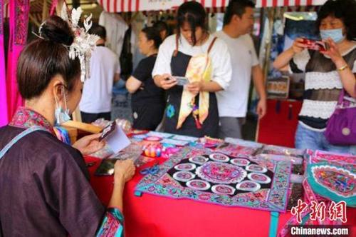 中国侨网非遗集市中,市民围观侗族刺绣。蒙鸣明摄