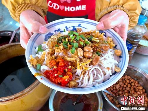 中国侨网5月24日,江西南昌,秦坚红的老店里,店员展示一碗刚制作好的南昌拌粉。在拌粉的调料台上,总有一盆不起眼的辣椒酱。中新社记者 刘力鑫 摄