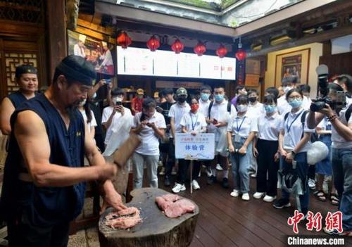 中国侨网图为同利肉燕传人陈君凡(左前)向研学体验营的学生展示肉燕制作技艺。 张斌 摄