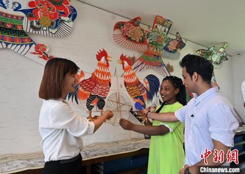 中国侨网第什里小镇风筝馆工作人员为两位留学生介绍第什里风筝。　翟羽佳　摄