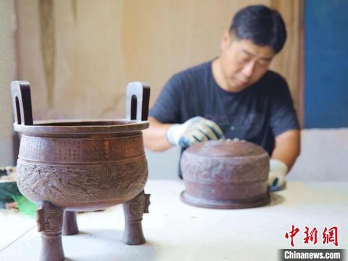 中国侨网灵寿青铜器制作工艺第五代传承人王英杰正在精修蜡模。　杨敏　摄