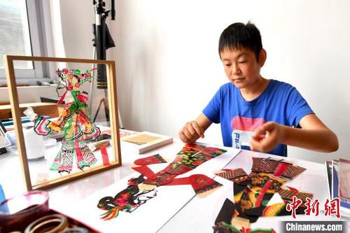 中国侨网图为王永跃正在将刚刚完成上色的皮影作品组件进行拼接。 刘建斌 摄