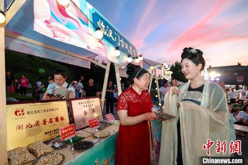 中国侨网游客在襄阳古城临汉门古风市集选购特色食品。 杨东 摄