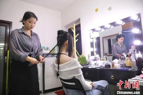 中国侨网26日,在成都一家汉服妆造工作室内,汉服妆造师李金芝(左)为汉服模特编发。中新网记者 王磊 摄
