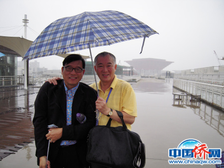 参加第五届世界华文传媒论坛，在雨伞下，拍下了世博会中国馆雄伟轮廓。作者与美洲中国日报发行人江启洸（左）。