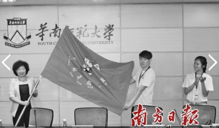 省侨办主任李心(左)向参加寻根夏令营的海外华裔优秀大学生代表授旗