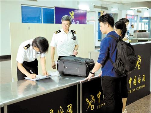 中国侨网海关关员在检查进境旅客行李物品。