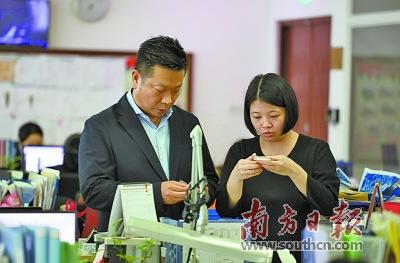 中国侨网李居仁(左)在位于珠海跨境工业区的办公室与同事交流。南方日报记者 关铭荣 摄