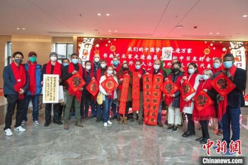 中国侨网在南昌高松中日友好会馆,参加本次活动的在昌外籍人士手拿对联春字和书画作品合影留念。 刘力鑫 摄