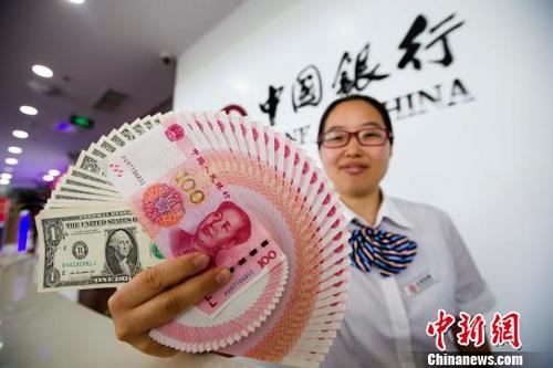 中国侨网资料图：山西太原，银行工作人员展示人民币、美元。　张云 摄