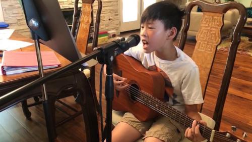 中国侨网近年来在南加州青少年歌唱、舞蹈、绘画、朗诵比赛中屡屡获奖的约巴林达八岁的张峻宁，利用暑期苦练弹唱和表演技巧。(美国《世界日报》/家长提供)