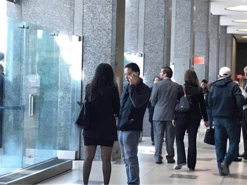 中国侨网嫌犯王玉芬的儿子(右)在法庭外等待王玉芬的审前听证。（美国《世界日报》/牟兰 摄）
