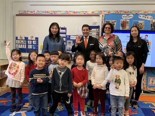 中国侨网纽约市教育总监卡兰扎(后排左二)在163小学校长Francine A. Marsaggi(后排左三)陪同下，与参与中英双语项目的学前班学生互动。（美国《世界日报》／赖蕙榆 摄）