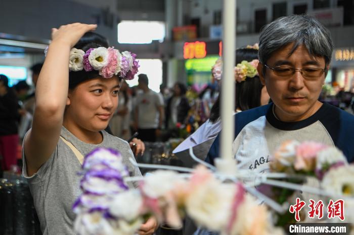 中国侨网6月24日,云南昆明,华裔青少年在斗南花卉市场购买鲜花花环。当日,来自美国华府青年义工俱乐部的华裔青少年、家长探访昆明国际花卉拍卖交易中心、昆明斗南花卉市场,感受云花产业的蓬勃生机,触摸中国绿色经济的澎湃动力。中新社记者 李嘉娴 摄